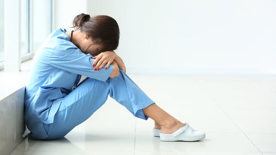 Stressed nurse sitting on floor in hallway